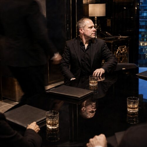 Barry Roberts seated at a black conference table during an evening meeting in London.
